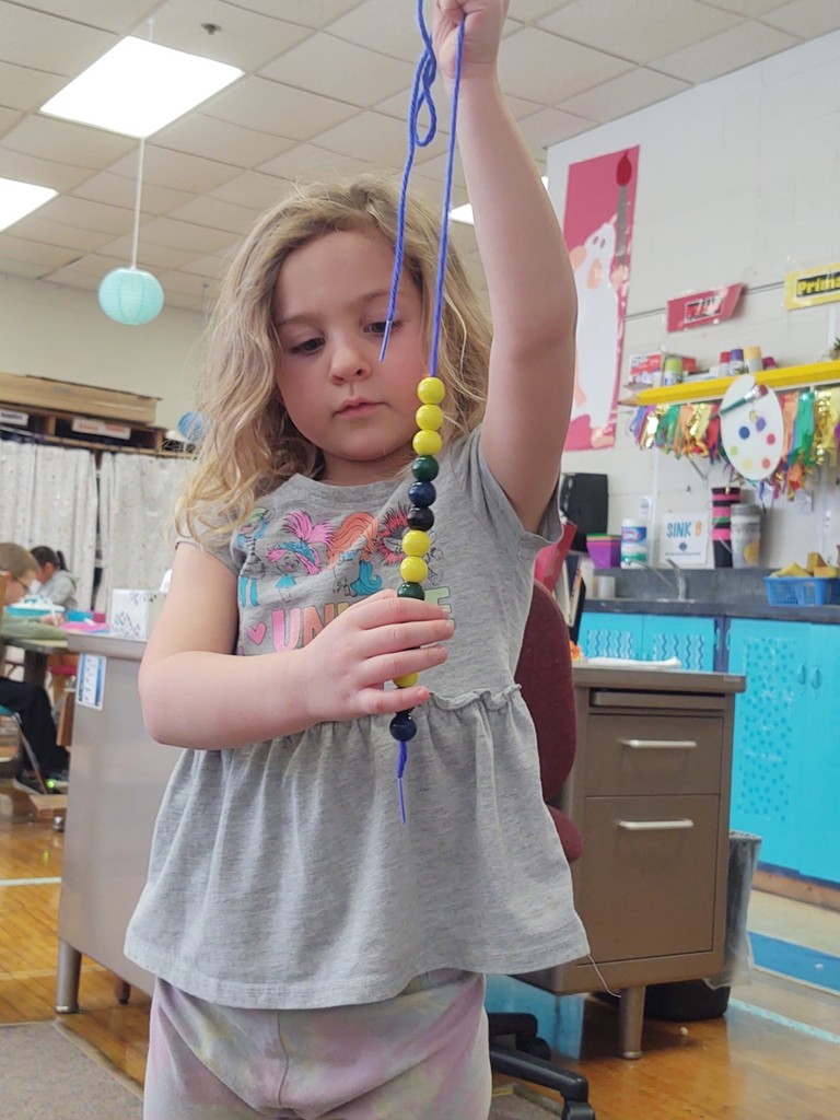 K & 1 exploring patterns with beads.